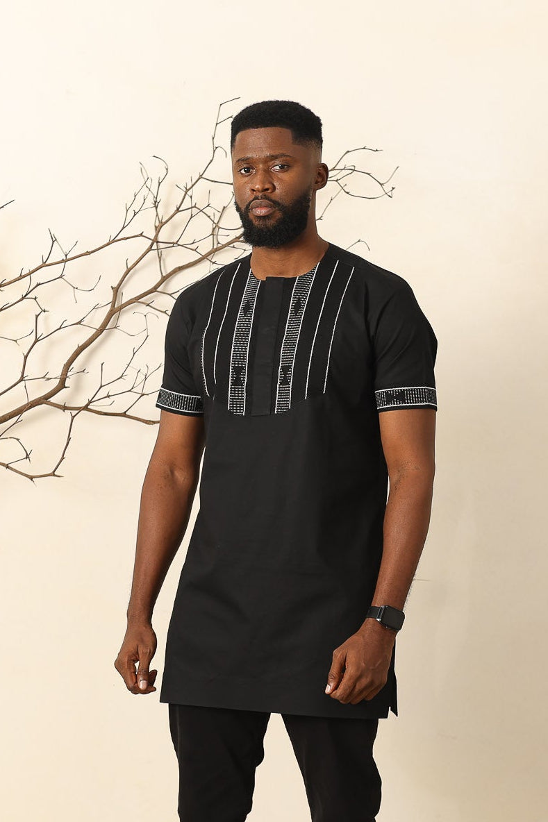 Man in a stylish African Print black outfit standing in a modern living room