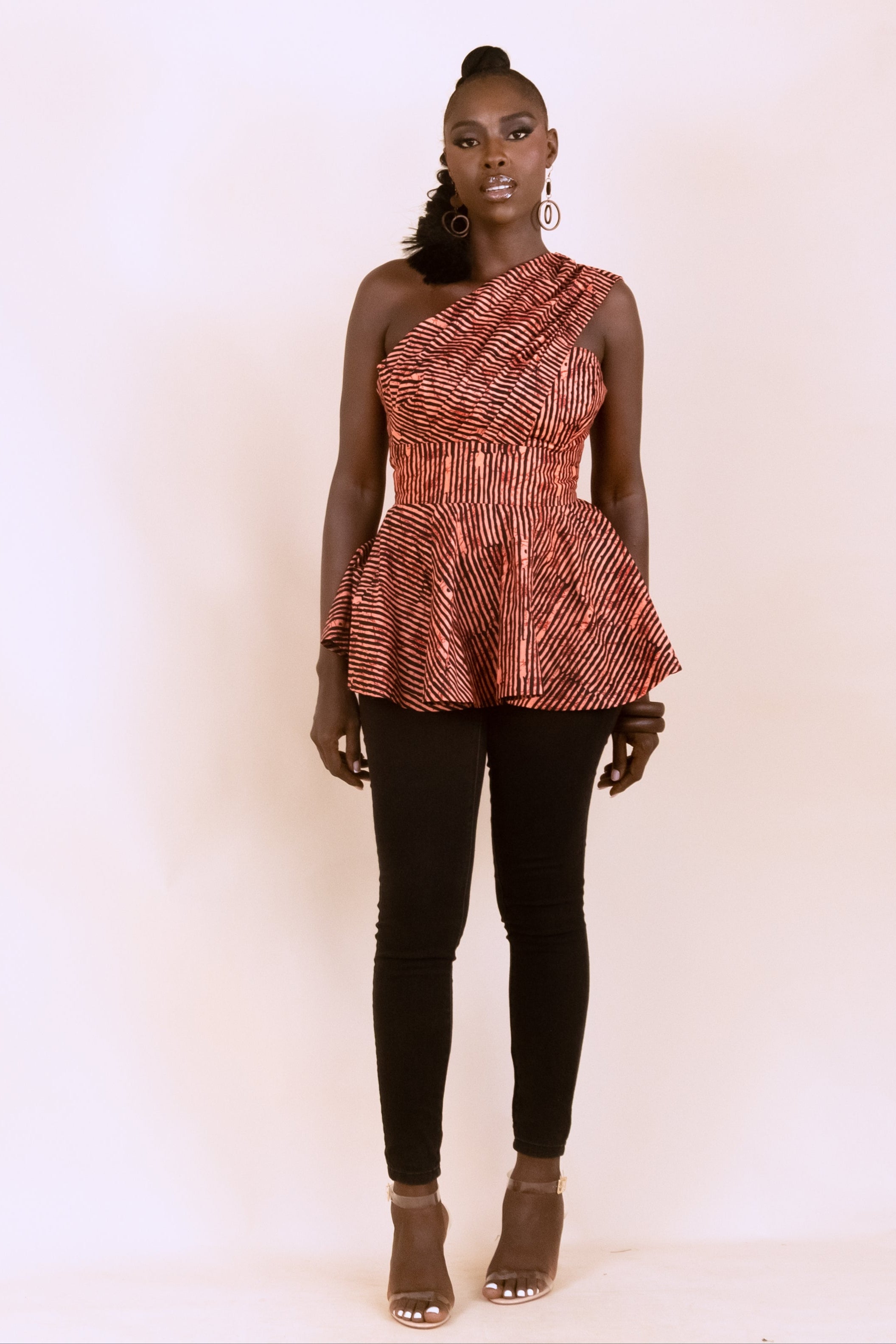 Woman wearing an orange and black striped Ankara print draped sleeve bustier top with peplum bottom.